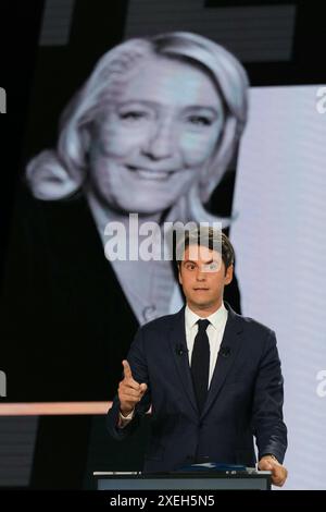 Le premier ministre français Gabriel Attal s’exprime devant un écran montrant une photo du chef du groupe parlementaire d’extrême droite rassemblement National (RN) à l’Assemblée nationale Marine le Pen lors d’un débat politique avec le premier secrétaire du Parti socialiste de gauche (PS) et député Olivier Faure et le président du parti d'extrême droite rassemblement National (RN) et eurodéputé principal Jordan Bardella ont diffusé sur la chaîne de télévision française France 2 à Paris le 27 juin 2024, à l'approche des élections anticipées en France pour une nouvelle Assemblée nationale. Photo Dimitar Dilkoff/Pool/ABACAPRESS. COM Banque D'Images