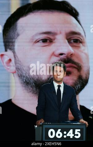 Paris, France. 27 juin 2024. Le premier ministre français Gabriel Attal se tient devant un écran montrant une photo du président ukrainien Volodymyr Zelensky lors d'un débat politique avec le premier secrétaire du Parti socialiste de gauche (PS) et député français Olivier Faure et le président et chef du parti d'extrême droite rassemblement National (RN) L'eurodéputé Jordan Bardella a diffusé sur la chaîne de télévision française France 2 à Paris le 27 juin 2024, à l'approche des élections anticipées en France pour une nouvelle Assemblée nationale. Photo Dimitar Dilkoff/Pool/ABACAPRESS. COM Credit : Abaca Press/Alamy Live News Banque D'Images