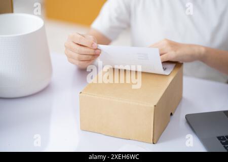 Le commerce des achats en ligne. Fixation de l'étiquette d'expédition à un colis. Banque D'Images