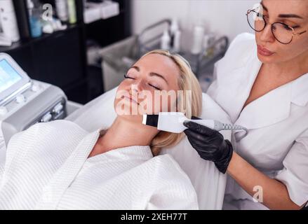 Maître de beauté fait peeling facial ultrasonique à son client. Banque D'Images