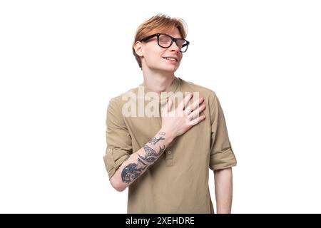 Jeune homme beau avec des cheveux de cuivre avec un tatouage sur son bras porte une chemise brune Banque D'Images