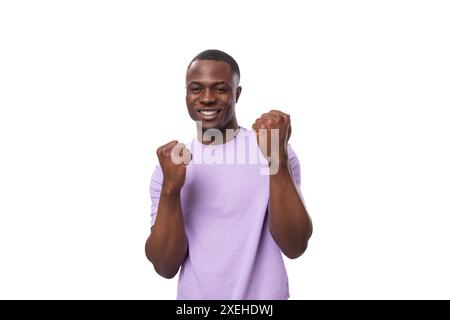 Portrait en gros plan du jeune homme américain heureux en t-shirt lilas sur fond blanc Banque D'Images