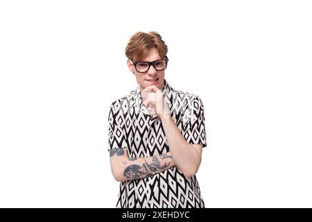 Jeune homme caucasien intelligent aux cheveux rouges avec des lunettes pour la vision dans une chemise d'été à manches courtes en noir et blanc Banque D'Images