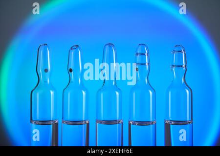 Plusieurs ampoules pour injection avec des médicaments sur un fond bleu. Banque D'Images