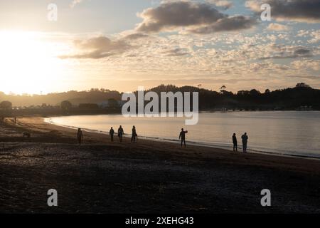 Les gens marchent au coucher du soleil sur la plage de te Ti Bay à Waitangi, Bay of Islands, Nouvelle-Zélande Banque D'Images