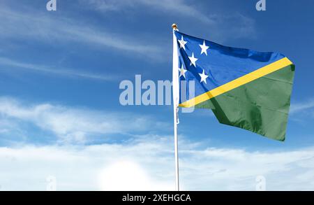 Drapeau des Îles Salomon sur ciel nuageux. ondulant dans le ciel Banque D'Images