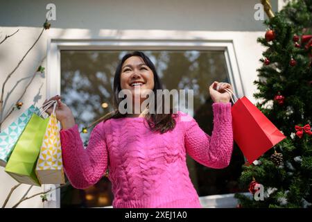 Joyeuse fille asiatique tenir des sacs à provisions cadeau de Noël. Femme joyeuse avec Noël nouvel an vente d'hiver Banque D'Images