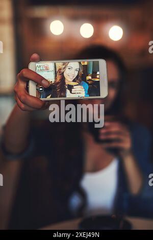 Main, écran et femme dans le café pour selfie, médias sociaux et créer des souvenirs pour la communauté en ligne. Influenceur féminin, coco chaud et souriant pour Banque D'Images