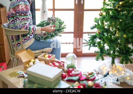 Femme fabriquant une couronne de gui décoration de couronne de Noël avec des mains de fleuriste de verdure d'hiver de bricolage faites à la main faisant de la wrea de Noël Banque D'Images