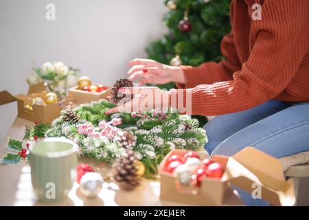 Femme fabriquant une couronne de gui décoration de couronne de Noël avec des mains de fleuriste de verdure d'hiver de bricolage faites à la main faisant de la wrea de Noël Banque D'Images