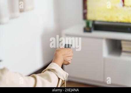 Femme âgée regardant la télévision intelligente et utilisant la télécommande main tenant la télévision audio télécommande Moyen âge Femme asiatique Banque D'Images