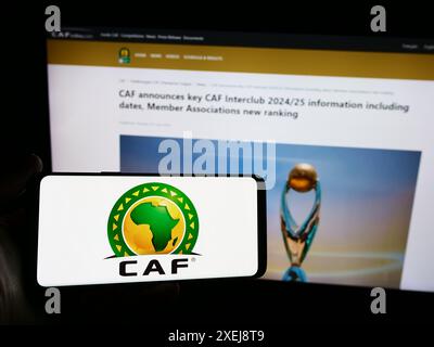 Personne tenant un smartphone avec logo de l'association Confederation africaine de Football (CAF) devant le site. Concentrez-vous sur l'affichage du téléphone. Banque D'Images