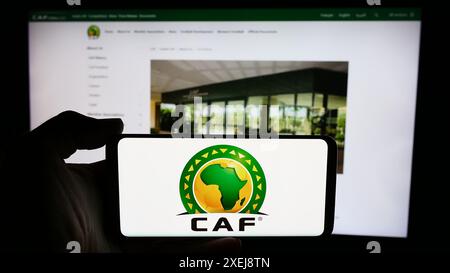 Personne tenant un téléphone portable avec le logo de l'association Confédération africaine de Football (CAF) devant la page web. Concentrez-vous sur l'affichage du téléphone. Banque D'Images