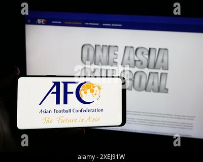 Personne tenant un smartphone avec le logo de l'association Asian Football Confederation (AFC) en face du site. Concentrez-vous sur l'affichage du téléphone. Banque D'Images