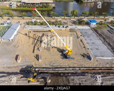 Travaux de construction au bord de la mer. La machinerie lourde travaille à renforcer les fondations de l'eau et des vagues de tempête. Vue depuis le drone. Banque D'Images