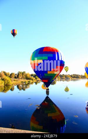 Ascension à l'aube de ballons vibrants au-dessus de l'eau Banque D'Images