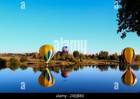 Ascension à l'aube de ballons vibrants au-dessus de l'eau Banque D'Images