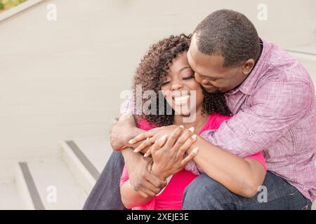 Homme tenant femme assise sur les marches riant ensemble Banque D'Images