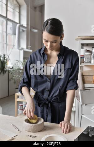 Céramiste asiatique travaille en studio debout au bureau de table artisanale Banque D'Images