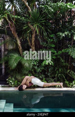 Jeune femme pratiquant le yoga au bord de la piscine Banque D'Images