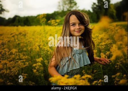 Gros plan belle jeune fille dansant dans le champ de fleurs jaunes Banque D'Images