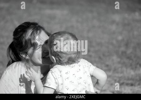 Mère et bébé partageant un moment proche à l'extérieur, noir et blanc Banque D'Images