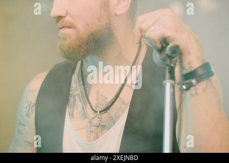 Gros plan moyen du leader barbu d'un groupe de rock posant sur la caméra avec microphone Banque D'Images