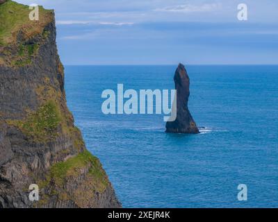 Majestueux Sea Stack s'élevant des eaux de l'océan bleu au large de la côte islandaise Banque D'Images