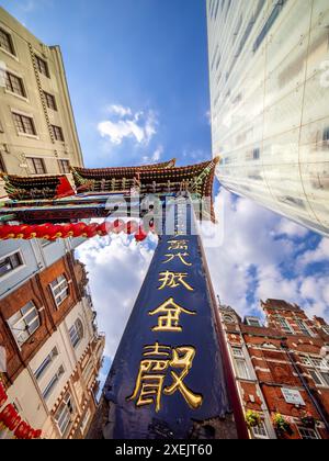 Londres, Royaume-Uni - 25 juin 2024 : vue vers le haut de la porte chinoise traditionnelle dans Chinatown Londres au milieu d'une architecture urbaine éclectique. Banque D'Images