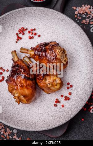 Délicieuses cuisses de poulet grillées aux épices et aux herbes, sauce teriyaki sur fond de béton foncé Banque D'Images