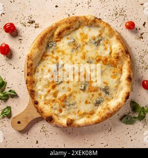 Pizza aux quatre fromages fraîchement cuite avec origan et tomates cerises sur fond de travertin texturé léger Banque D'Images