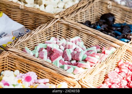 Gros plan, vue détaillée de bonbons rouges, blancs et verts à la pastèque et des bonbons dans des paniers en osier entourés d'un assortiment de plats à l'ancienne Banque D'Images