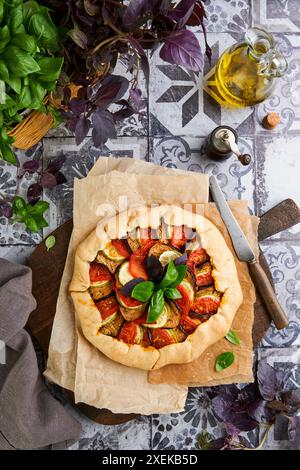 Galette ratatouille aux aubergines, courgettes, tomates. Plat français traditionnel fait maison avec des ingrédients et des ustensiles de cuisine sur la vieille table de tuiles backgrou Banque D'Images