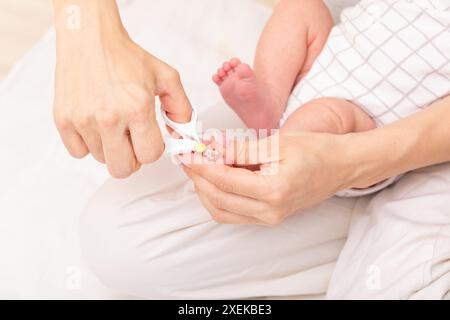 La mère utilise des ciseaux spéciaux pour ongles de bébé pour couper les ongles du bébé nouveau-né Banque D'Images