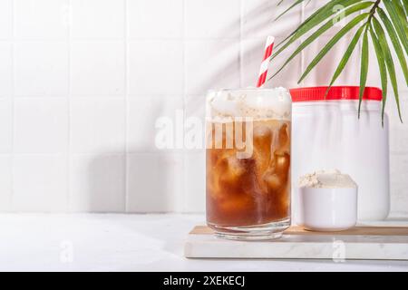 Verre de boisson au café latte collagène avec de la poudre de collagène dans un pot et une cuillère, sur une table de cuisine blanche. Supplément naturel pour la beauté, la santé de la peau, les os, Banque D'Images