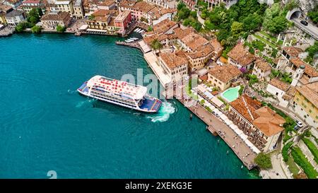 Limone, Lac de Garde, Italie - 26 juin 2024 : Limone sur le Lago di Garda ou le Lac de Garde, au port de Limone sul Garda, un ferry ou un bateau accoste. Vous pouvez voir la vieille ville d'en haut avec les restaurants et les hôtels de la petite ville touristique. *** Limone am Lago di Garda bzw. Gardasee, Am Hafen von Limone sul Garda, legt eine Fähre an, bzw. ein Schiff. Zu sehen ist die Altstadt von oben mit restaurants und Hotels des kleinen Touristen-Ortes. Banque D'Images