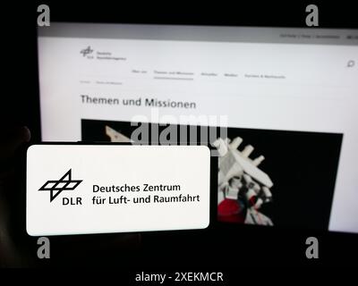 Personne tenant un smartphone avec le logo de Deutsches Zentrum für Luft- und Raumfahrt e.V. (DLR) devant le site. Concentrez-vous sur l'affichage du téléphone. Banque D'Images