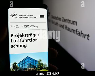 Personne tenant le téléphone portable avec la page web de Deutsches Zentrum für Luft- und Raumfahrt e.V. (DLR) avec le logo. Concentrez-vous sur le centre de l'écran du téléphone. Banque D'Images