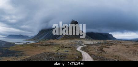 Route de terre sinueuse menant à la chaîne de montagnes Foggy en Islande Banque D'Images