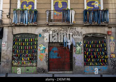 Façade d'un bâtiment décoré de dessins et de graffitis et jeans avec des chaussures dans le quartier Malasana de Madrid ; Madrid, Espagne Banque D'Images