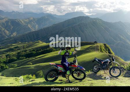 Pilote de moto pose avec excitation devant le magnifique paysage impressionnant derrière lui à Sulawesi du Sud, en Indonésie Banque D'Images