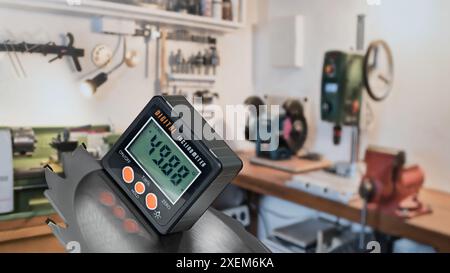 Inclinomètre numérique pour mesurer l'angle de pente d'une lame de scie circulaire. Rapporteur électronique en atelier. Meuleuse d'établi, étau manuel, perceuse, tour. Banque D'Images