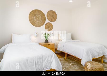 chambre moderne bohème avec lits jumeaux, table de chevet, tapis et décoration murale en osier. vue latérale Banque D'Images