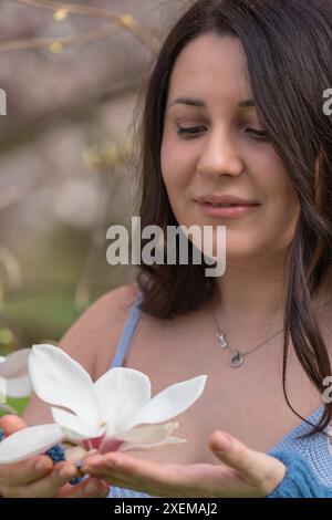 Une femme tient une grande fleur de magnolia dans ses mains. Gros plan Banque D'Images