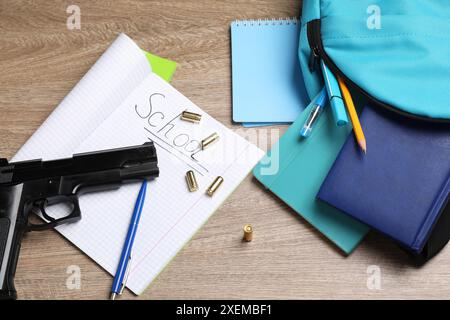 Arme à feu, balles et papeterie scolaire sur table en bois, pose à plat Banque D'Images