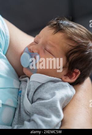 La tête de bébé dans les mains de la mère. Maman tient un garçon nouveau-né, le bébé dort doucement. Santé et développement du nourrisson. La naissance d'un enfant et l'amour de p Banque D'Images