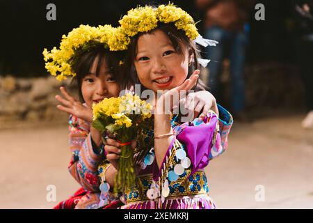 Filles hmong avec guirlande florale sur la tête, posant pour la caméra ; Pa Co, mai Chau, son la, Vietnam Banque D'Images