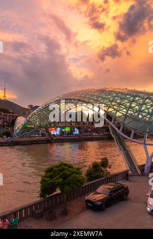 Tbilissi, Géorgie - 16 juin 2024 : le pont de la paix est un pont piétonnier en forme d'arc, une construction en acier et en verre au-dessus de la rivière Kura, reliant t Banque D'Images