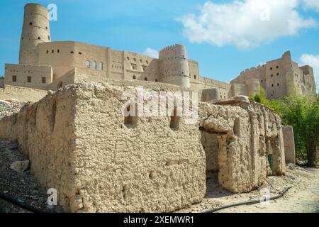 Bahla citadelle forteresse murs en pierre et tours rondes avec vieux bâtiment au premier plan, Bahla, Oman Banque D'Images