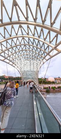 Tbilissi, Géorgie - 16 juin 2024 : le pont de la paix est un pont piétonnier en forme d'arc, une construction en acier et en verre au-dessus de la rivière Kura, reliant t Banque D'Images